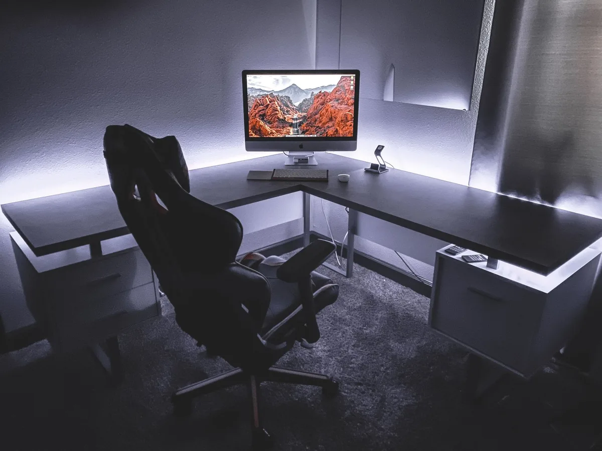 L-shaped gaming desk with multiple monitors, mixer and streaming equipment