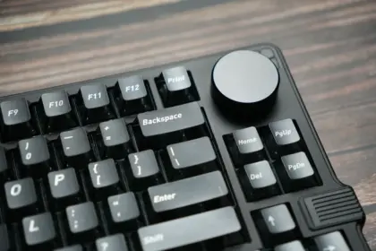 Close-up of hands typing on a mechanical gaming keyboard with illuminated keys.