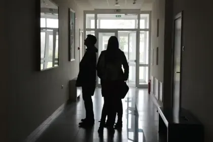 Dim maze-like corridor with silhouetted figures and a single door casting light
