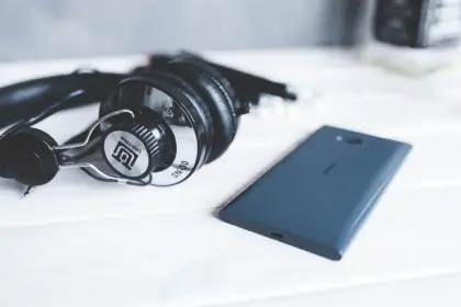 Hand holding a smartphone and vintage headphones with vinyl records in the background