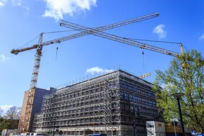 Theme park construction site with cranes and scaffolding over themed land structures and blueprints