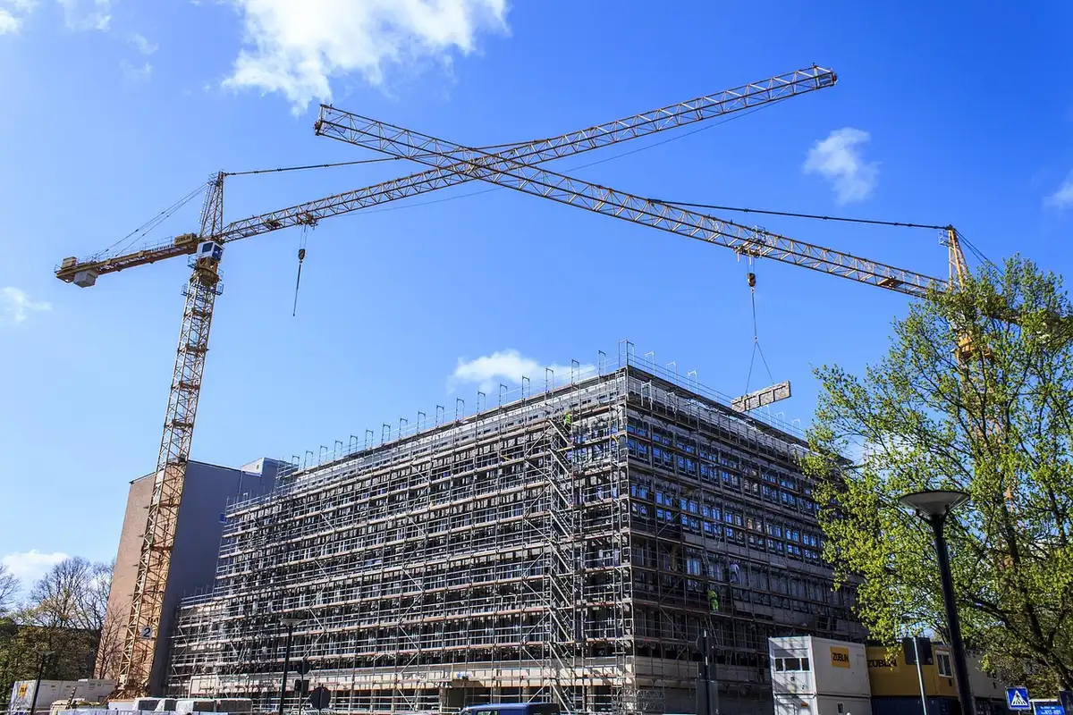 Theme park construction site with cranes and scaffolding over themed land structures and blueprints