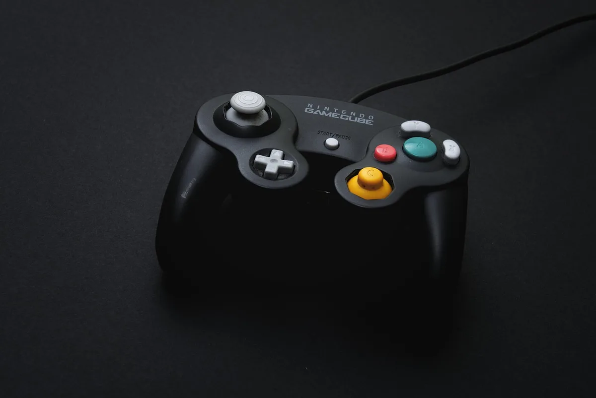 Controller on a couch with a TV showing a game menu, daylight through windows