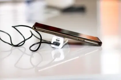 Hands swapping a battery into a modern game controller beside a small wired docking station