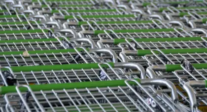 Hands holding a gaming console at a retail checkout with price tags visible on shelves