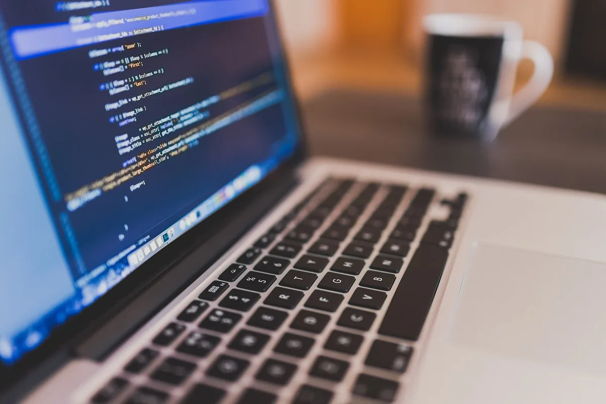 Laptop on a coffee table showing code beside a TV, used in AI-guided setup