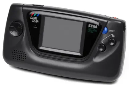Hands inserting a game cartridge into a handheld console on a bright tabletop