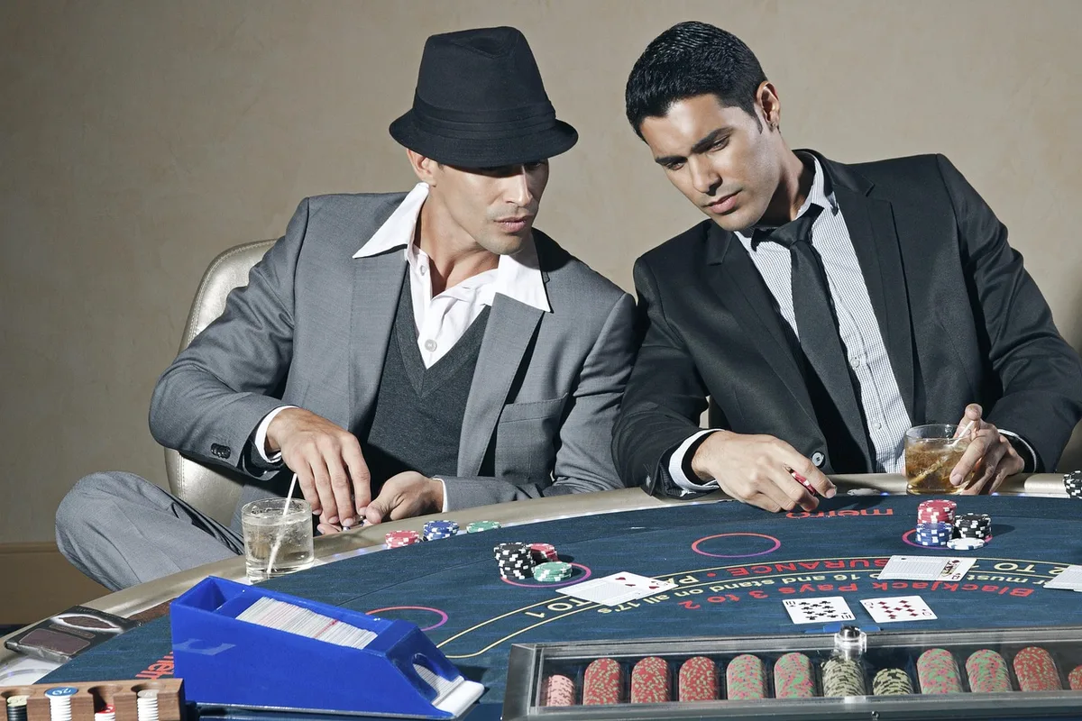 Group playing cards at a sunlit outdoor table, evoking low-stakes downtime and social moments