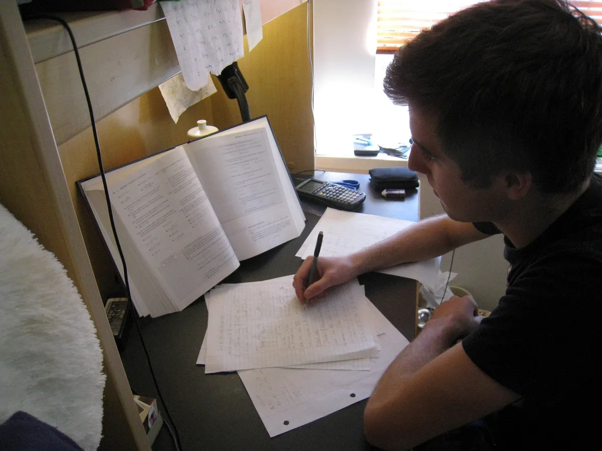 Person reviewing notes and a laptop preparing for a quiz