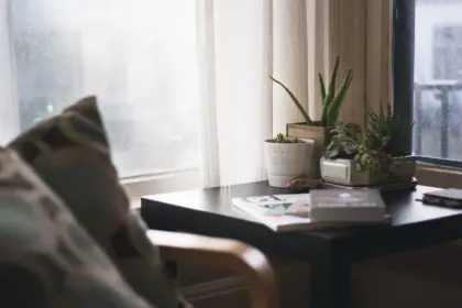 Bright living room with tablet showing football score, mug and folded scarf on sofa