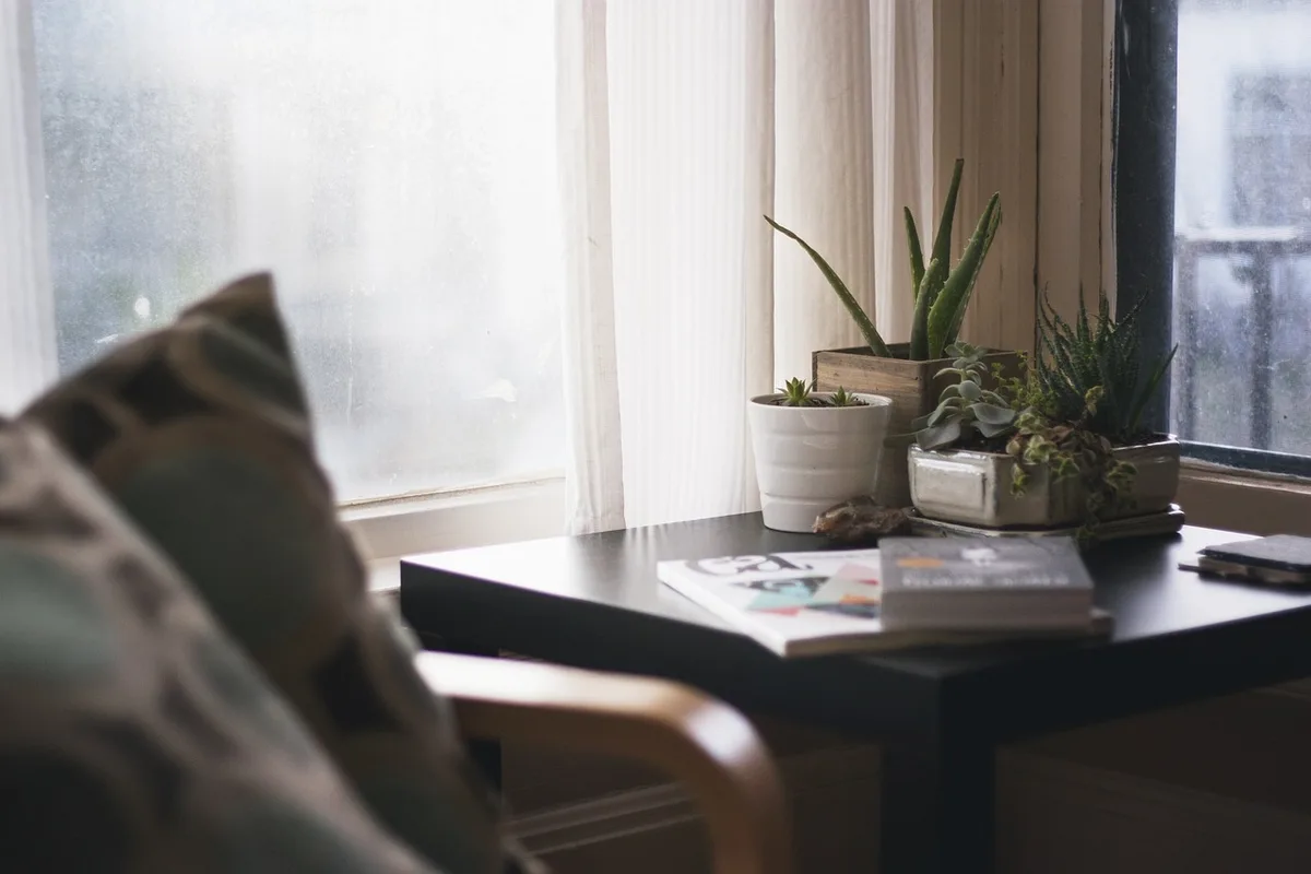 Bright living room with tablet showing football score, mug and folded scarf on sofa